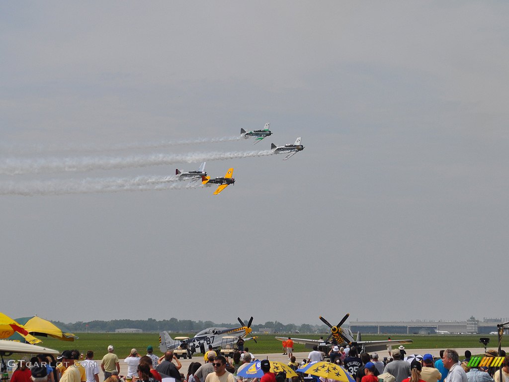 4 T-6 Trainers in the air and 2 P-51 Mustangs on the taxiway